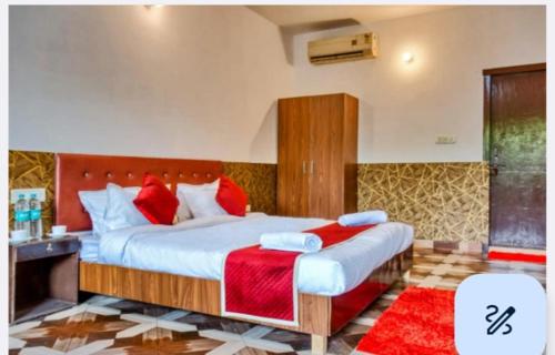 a bedroom with a large bed with red pillows at CAMP BIG CAT CORBETT, Hotel Resort booking, Dhikuli, Near Kosi River, garjiya Bijrani Sitabani Safari ZonesJim Corbett Park, Ramnagar in Garjia
