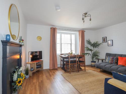 a living room with a couch and a dining room table at 1 Tyn Y Gongl Cottage in Beaumaris