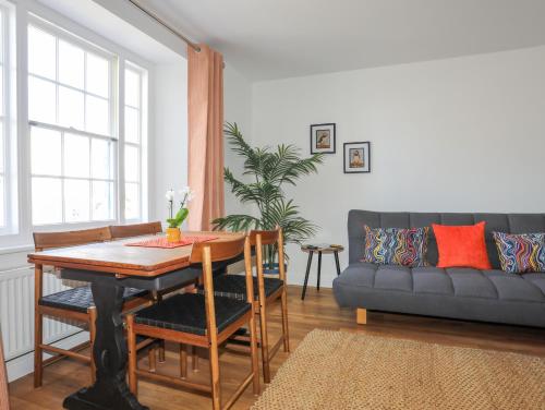 a living room with a table and a couch at 1 Tyn Y Gongl Cottage in Beaumaris