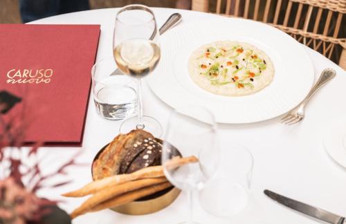 a white table with a plate of food and a glass of wine at Grand Hotel et de Milan - The Leading Hotels of the World in Milan