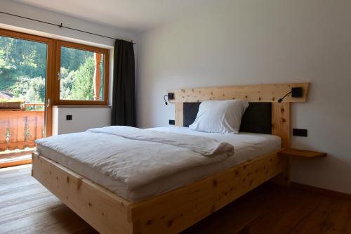 a bedroom with a wooden bed with a large window at Biobauernhof Obermühle in Mittersill