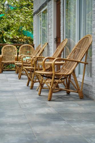 a row of wicker chairs sitting on a porch at Kayyath Valley Munnar - Luxury 4BHK Hillside Sanctuary in Anachal