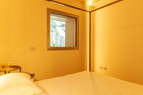 a yellow room with a bed and a window at La Forestale Luxury Ecolodge B&B Primo Piano in Acqualagna