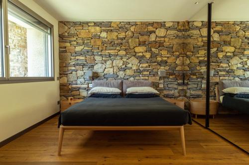 a bed in a room with a stone wall at La Forestale Luxury Ecolodge B&B Primo Piano in Acqualagna