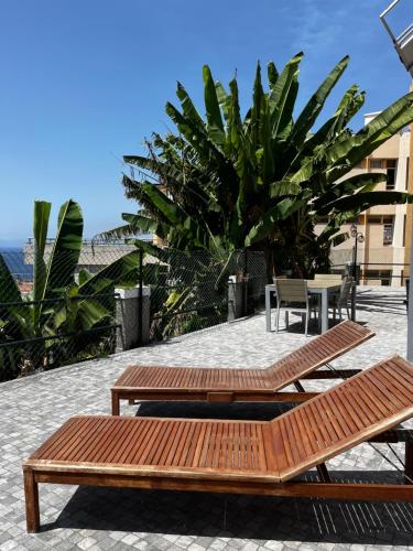 two wooden benches sitting on top of a patio at Lazareto 148 Hostel in Funchal