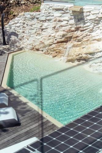 a swimming pool next to a stone wall at La Forestale Luxury Ecolodge B&B Primo Piano in Acqualagna