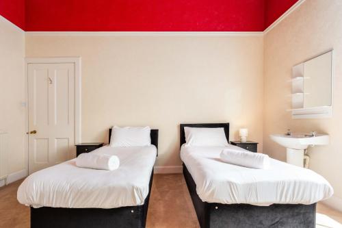 two beds in a room with a red ceiling at Burnock Lodge with Hot Tub in Ayr