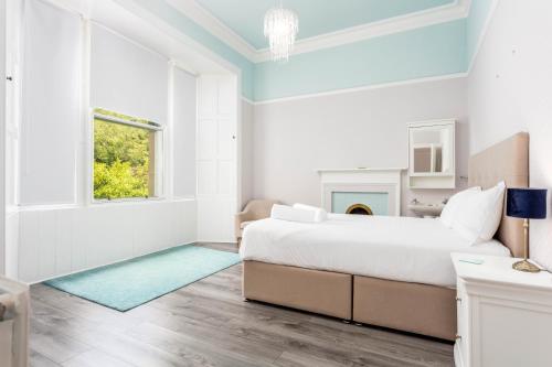 a white bedroom with a large bed and a fireplace at Burnock Lodge with Hot Tub in Ayr