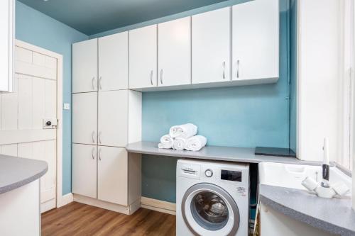 a kitchen with white cabinets and a washing machine at Burnock Lodge with Hot Tub in Ayr