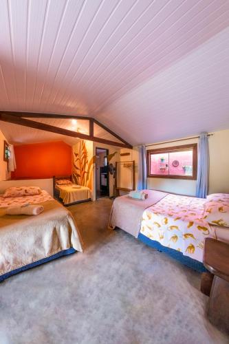 a bedroom with two beds and a chair in it at Seriema Hospedagem - Vila de São Jorge in Sao Jorge