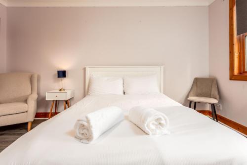 a bedroom with a white bed with towels on it at Burnock Lodge with Hot Tub in Ayr