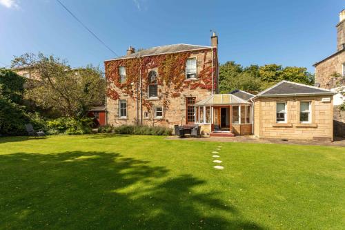 an old brick house with a grass yard at Burnock Lodge with Hot Tub in Ayr