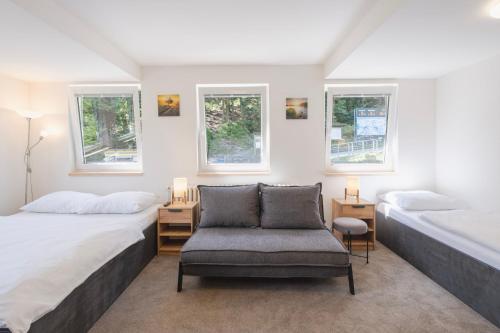 a bedroom with two beds and a chair and windows at CHATA LESOVNA in Pec pod Sněžkou