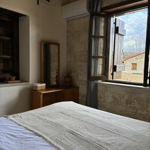 a bedroom with a white bed and a window at Levanda House - Traditional House in Vasa Kilaniou