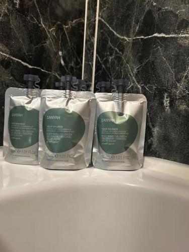 three bottles of soap sitting on top of a bath tub at No 12 Bridge Street - Town Centre Apartment in Westport