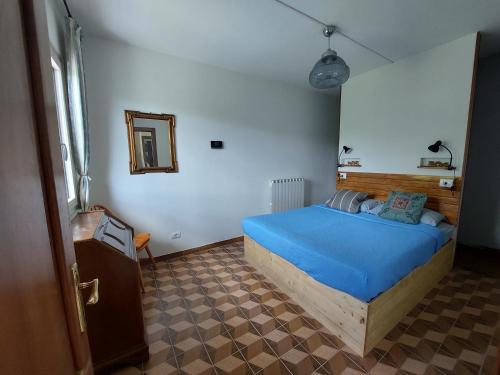 a bedroom with a blue bed and a mirror at casa Donadiolla in Maiola