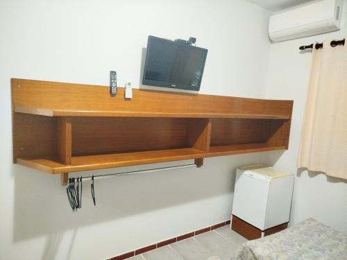 a television on a wooden shelf in a room at Hotel Xapuri in Peruíbe