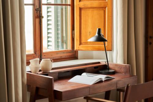 a desk with a lamp and a book in front of a window at Precise Tale Poggio Alla Sala in Montepulciano
