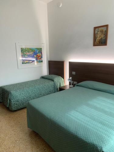 a hotel room with two beds with green sheets at Locanda Al Santuario in Peschiera del Garda
