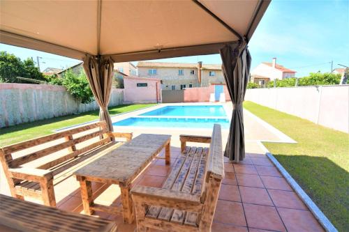 gazebo con tavolo, sedie e piscina di Casa das Roma a Cambados