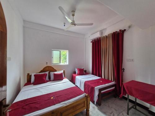two beds in a room with red curtains at TRINCO VISTARA GUEST House in Trincomalee