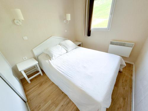 une petite chambre avec un lit blanc et une fenêtre dans l'établissement Valmeinier, à Valmeinier