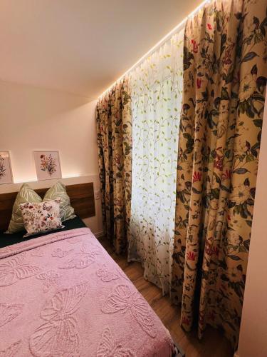 a bedroom with a pink bed and a curtain at Sparrow apartmens - Superior family in Košice