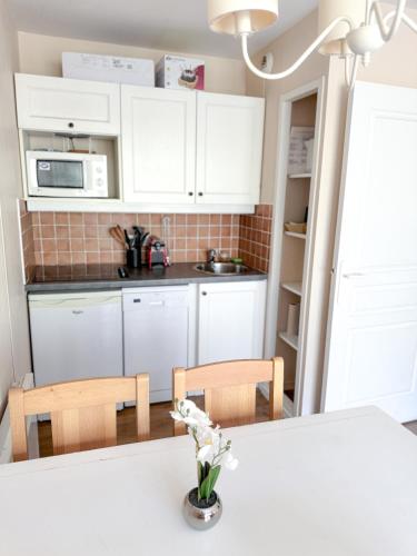 - une cuisine avec des placards blancs et une table fleurie dans l'établissement Valmeinier, à Valmeinier