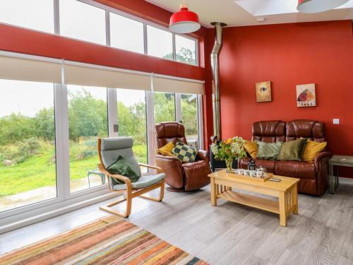 una sala de estar con paredes rojas y muebles de cuero. en Tirlaggan House, en Oban