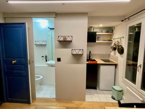 Il comprend une petite cuisine avec une porte bleue et une salle de bains. dans l'établissement Très joli Studio - centre Paris - Le Coeur du Marais, à Paris