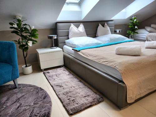a bedroom with a large bed and a blue chair at Wellness Apartmány EMPORIO in Loštice