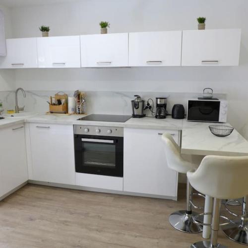 - une cuisine blanche avec une cuisinière et une table dans l'établissement Appartement en plein centre à 100m du port, à Mèze