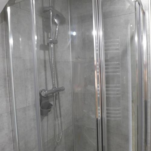 une douche avec une porte vitrée dans une salle de bain dans l'établissement Appartement en plein centre à 100m du port, à Mèze