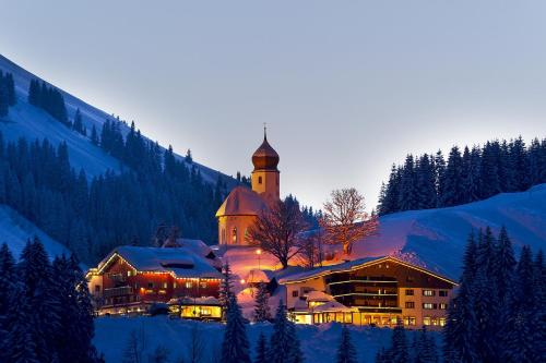 a large building with a clock tower in the snow at Gasthaus Ursprung in Damuls