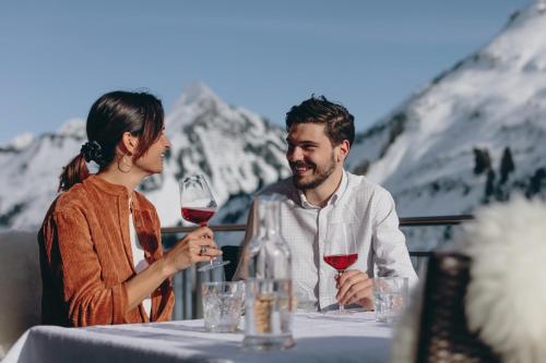 a man and woman sitting at a table with wine glasses at Gasthaus Ursprung in Damuls