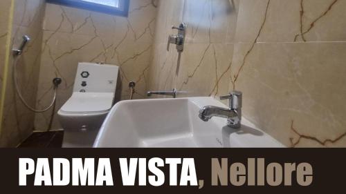 a bathroom with a white sink and a toilet at Hotel Padma Vista Nellore Near Bus Stop in Nellore