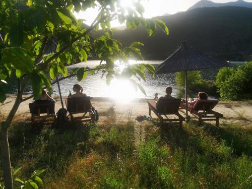 a group of people sitting on benches by a lake at Agroturizem Hotel Vila Franceze in Koman