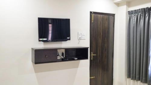 a room with a tv on the wall next to a door at Hotel Padma Vista Nellore Near Bus Stop in Nellore