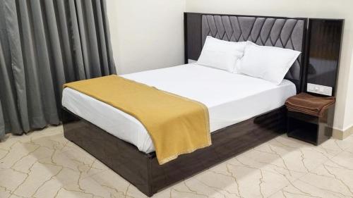 a bedroom with a white bed with a wooden headboard at Hotel Padma Vista Nellore Near Bus Stop in Nellore