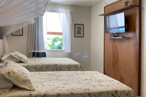 a bedroom with two beds and a flat screen tv at Bonito Paraiso Ilha Grande in Abraão