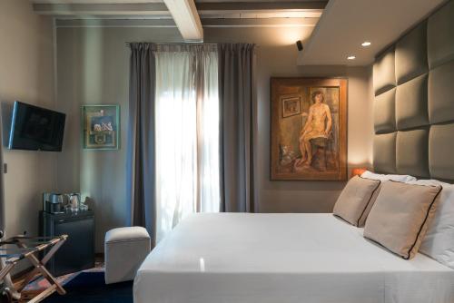 a bedroom with a white bed and a painting on the wall at Sunset Villa in Castiglione della Pescaia