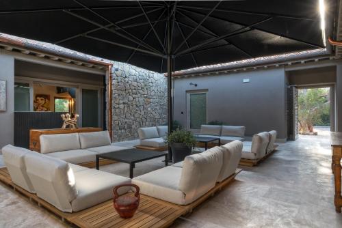 a living room with white furniture and a stone wall at Sunset Villa in Castiglione della Pescaia