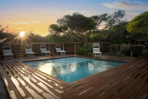 a swimming pool with chairs on a wooden deck at Sunset Villa in Castiglione della Pescaia