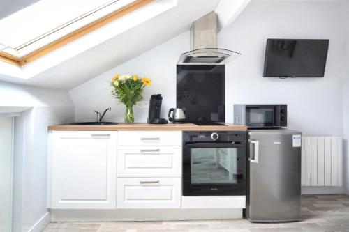 une cuisine avec des armoires blanches et un appareil noir dans l'établissement Le 20 Bis - Second Souffle - Cherbourg, à Cherbourg en Cotentin