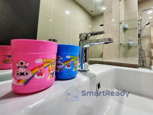 two pink and blue cups sitting on a bathroom sink at Sunway GRID by SR Home in Kampong Pendas