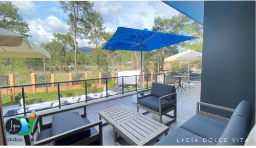 a patio with a table and chairs and a blue umbrella at LYCIA DOLCE ViTA OLYMPOS ANTALYA in Kumluca