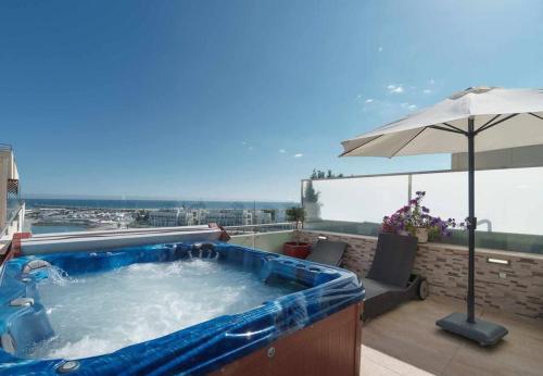 a hot tub on a balcony with an umbrella at VilamouraSun Aquamar Penthouse 601 in Quarteira