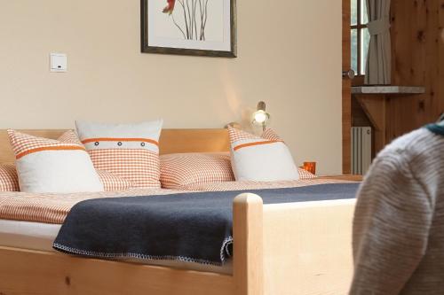 a bed with orange and white pillows on it at Aussermahrhof - familyfarm in Gsies