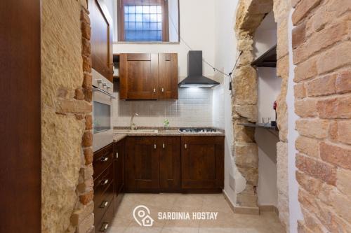 a kitchen with wooden cabinets and a brick wall at Living Villanova Apartment in Cagliari