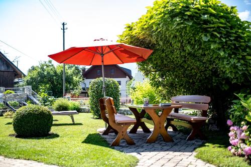 a table and chairs with an umbrella in a garden at Gästehaus im Wiesengrund in Sankt Stefan an der Gail